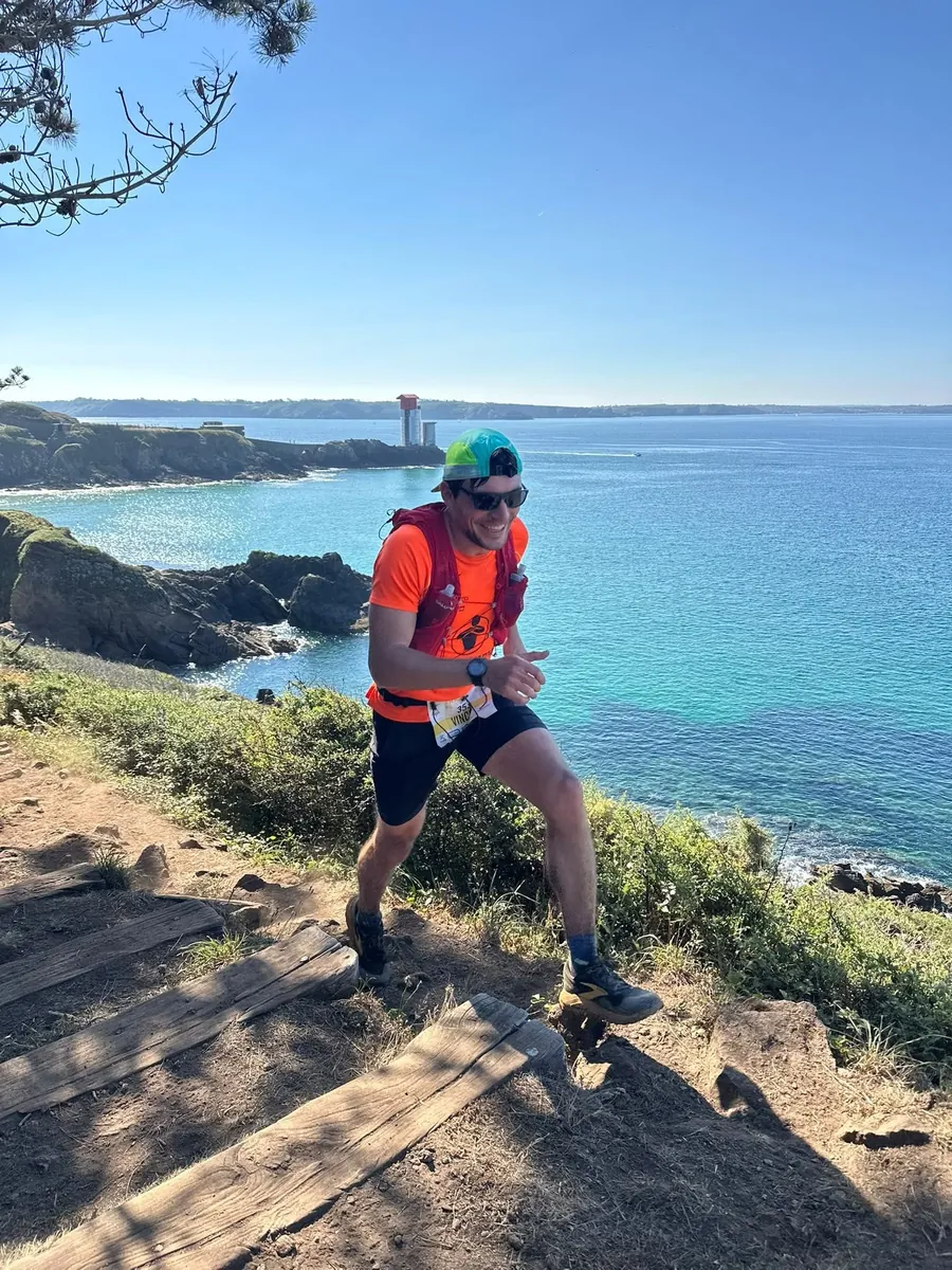 Un coureur du club en maillot orange sur un sentier côtier